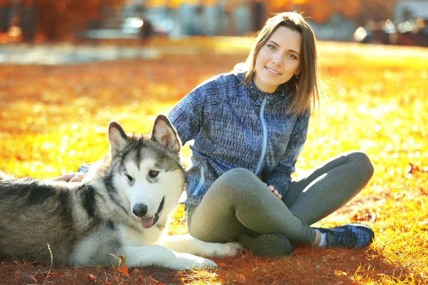 Vrouw zitten met haar hond op gras in park — Stockfoto