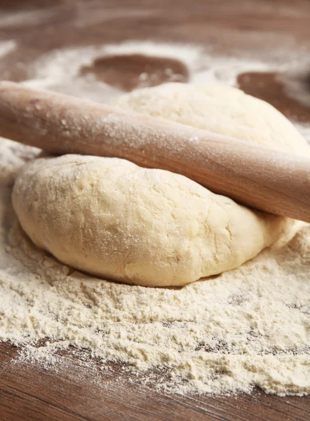 Dough for pizza and rolling-pin on wooden table — Stock Photo, Image