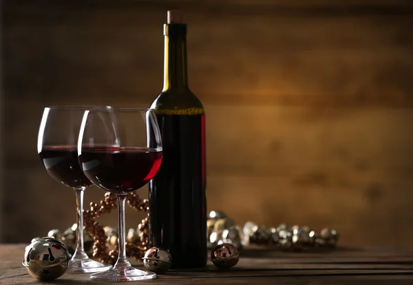 Red wine and Christmas ornaments on wooden table on wooden background — Stock Photo, Image
