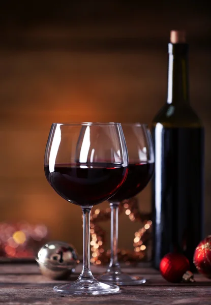 Red wine and Christmas ornaments on wooden table on wooden background — Stock Photo, Image