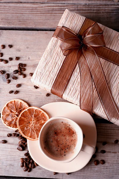 Vacker gåva, kopp med kaffe och kaffe korn på trä bakgrund — Stockfoto