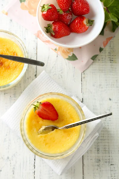 Postre de crema brulee con fresas frescas y hojas de menta, sobre fondo de madera de color — Foto de Stock