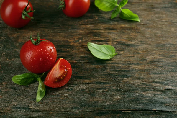 Pomodori ciliegia con basilico sul tavolo di legno da vicino — Foto Stock