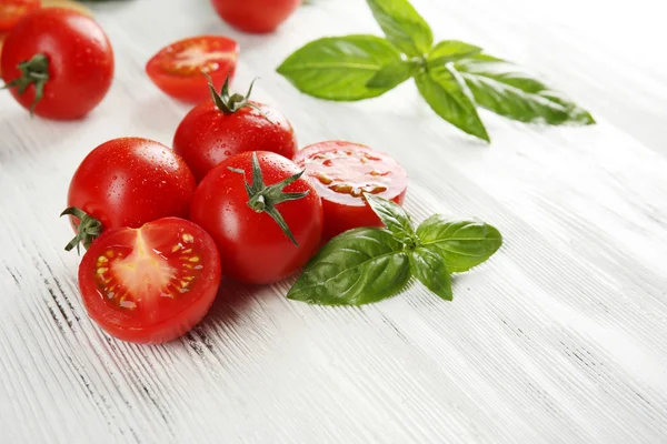 Cherry tomatoes with basil on wooden table close up — Stock Photo, Image