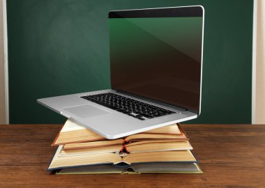 Dizüstü bilgisayar ile kitap yığını