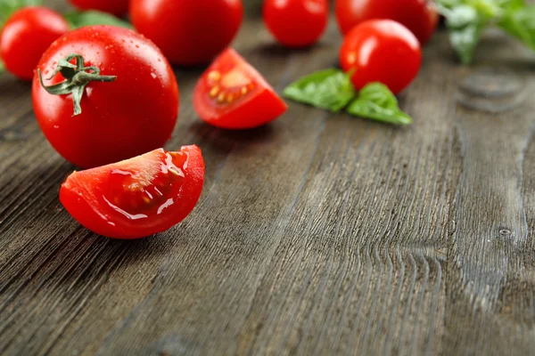 Fresh tomatoes with basil on wooden table close up — Stock Photo, Image