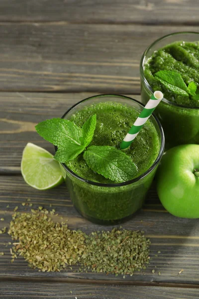 Зеленый здоровый сок с фруктами и травами на деревянном столе вблизи — стоковое фото