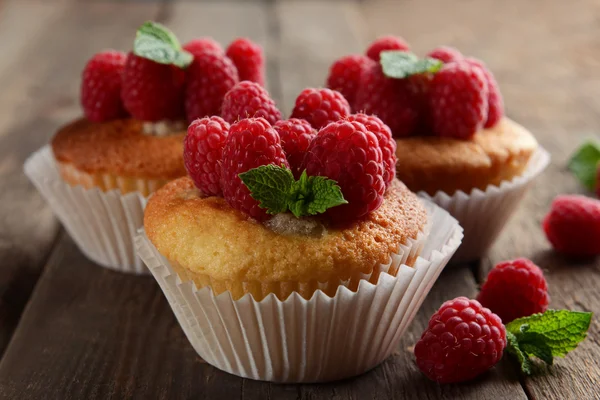 Deliciosos cupcakes con bayas y menta fresca en la mesa de madera de cerca —  Fotos de Stock