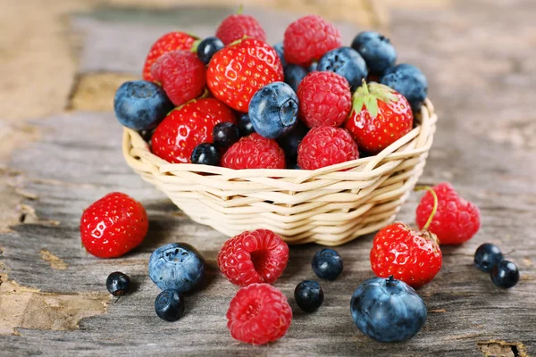 Sweet tasty berries in basket on wooden table close up — Stock Photo, Image
