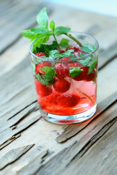 Glas kaltes erfrischendes Sommergetränk mit Beeren und Eiswürfeln auf dem Tisch in Großaufnahme — Stockfoto