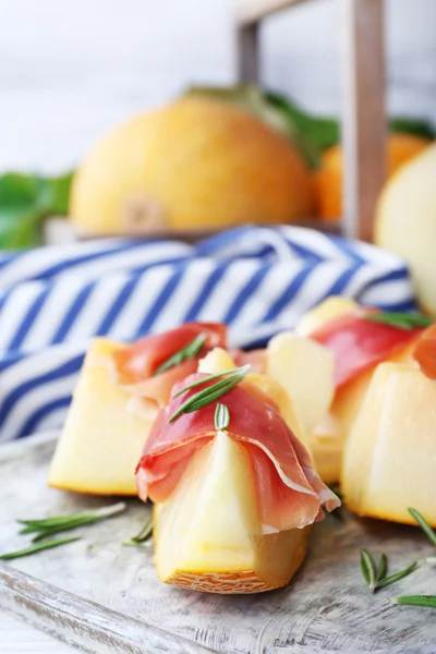 Melon with prosciutto of Parma ham on wooden table, closeup — Stock Photo, Image