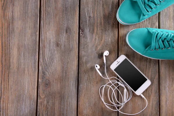 Мобильный телефон с наушниками и резиновыми туфлями — стоковое фото