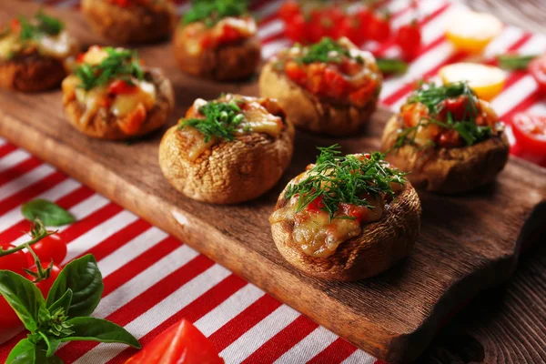 A wooden tablet with stuffed mushrooms and vegetables on the table — Stock Photo, Image