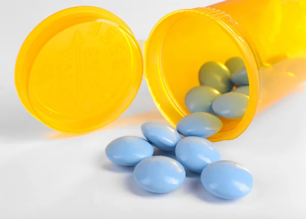 Blue drugs spilled from yellow bottle — Stock Photo, Image