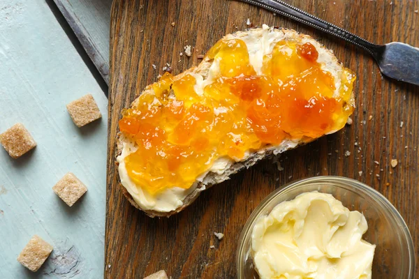 Νόστιμο φρέσκο ψωμί με μαρμελάδα και βούτυρο σε ξύλινα φόντο — Φωτογραφία Αρχείου