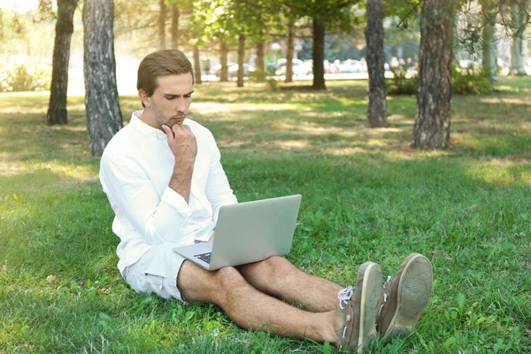 Man met laptop op groen gras — Stockfoto