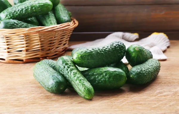 Rijp komkommers in rieten vaas op tafel — Stockfoto