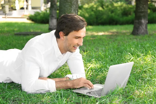 Man with laptop on green grass — Stock Photo, Image