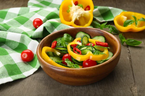 Gemüsesalat mit Gurken auf Holzgrund, dekoriert mit grün karierten Baumwollservietten und Paprika — Stockfoto