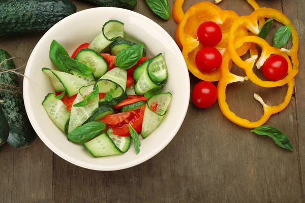 Ensalada de verduras con pepinos y pimienta sobre fondo de madera — Foto de Stock