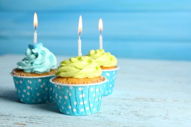 Ahşap arka plan mavi mum ile tatlı lezzetli cupcakes