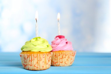 Arka plan bulanık karşı mavi ahşap masa mum ile lezzetli cupcakes