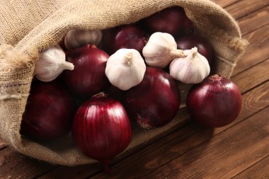 Kırmızı soğan ve sarımsak ahşap arka plan üzerinde dağınık çanta