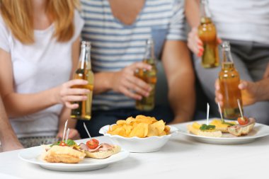 Arkadaşlar el ile şişe bira ve aperatifler, yakın çekim