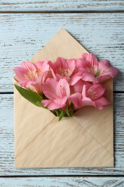 Ahşap arka plan üzerinde zarf içinde pembe alstroemeria