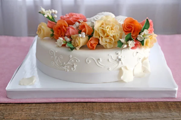 部屋のテーブルの上に花で飾られたエレガントなウェディング ケーキ — ストック写真