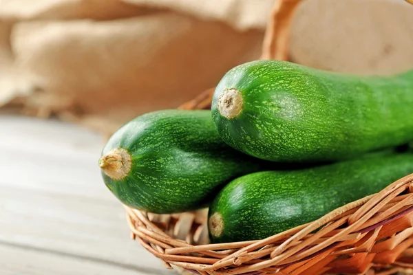 Fresh zucchini in wicker basket on wooden background — Stock Photo, Image