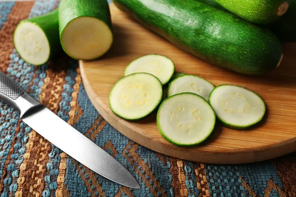 Fresh sliced zucchini on cutting board, on wooden background — Stock Photo, Image