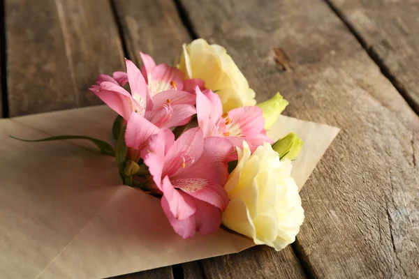 Weißes Eustoma und rosa Alstroemeria im Umschlag auf Holzgrund — Stockfoto