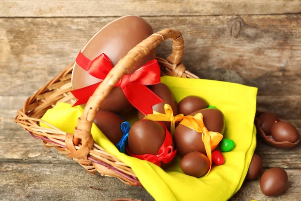 Chocolate Easter eggs in basket on wooden background — Stock Photo, Image