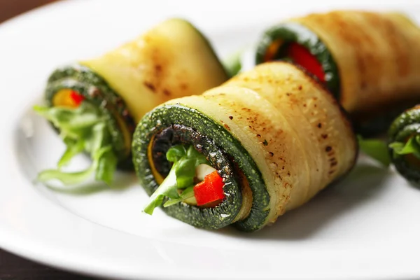 Rollos de calabacín con queso, pimientos y rúcula en el plato, primer plano — Foto de Stock