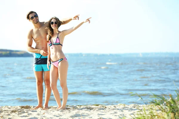 Pareja feliz apuntando a la playa — Foto de Stock