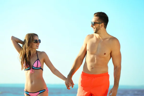 Pareja feliz cogida de la mano en la playa — Foto de Stock