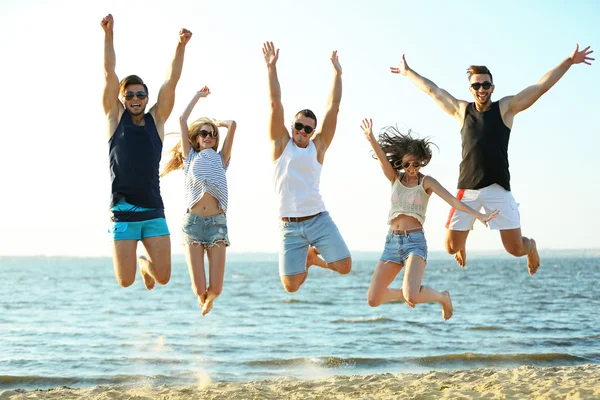 Des amis heureux sautant à la plage — Photo