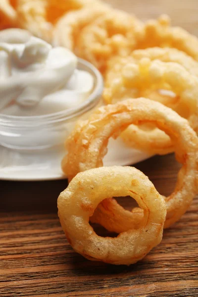 Chips-Ringe mit weißer Sauce auf Teller auf hölzernem Hintergrund — Stockfoto