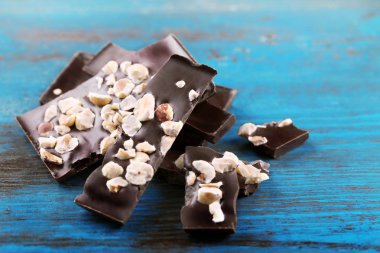 Fındık rengi ahşap arka plan üzerinde siyah çikolata parçaları