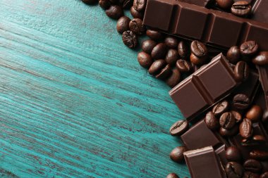 Siyah çikolata parçaları ve renk ahşap arka plan üzerinde kahve taneleri