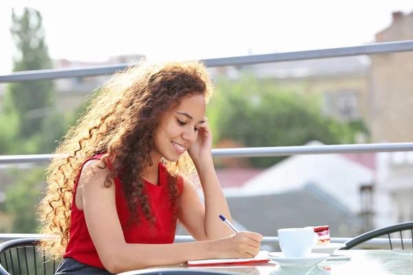 Femme souriante en robe rouge fait la notation — Photo