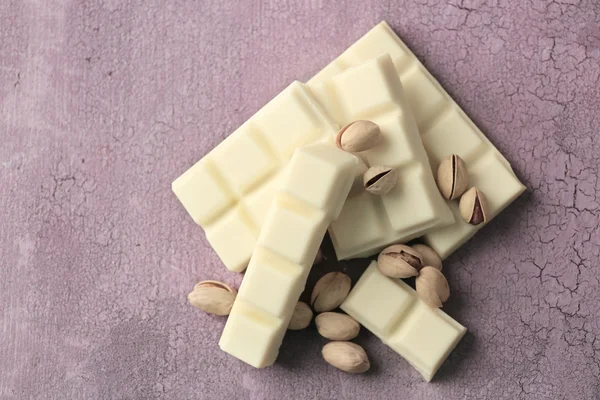 Potongan cokelat putih dengan kacang pada warna latar belakang kayu — Stok Foto