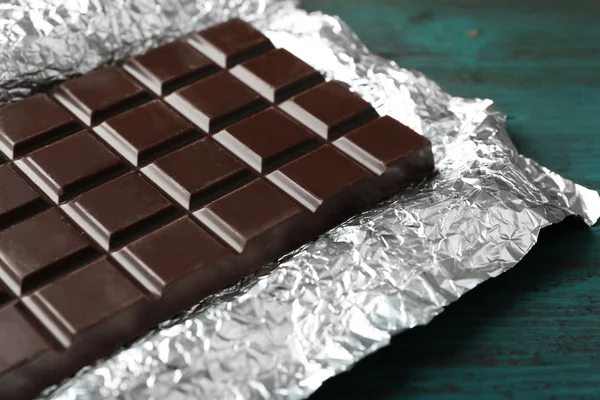 Barra de chocolate negro en papel de aluminio sobre fondo gris —  Fotos de Stock