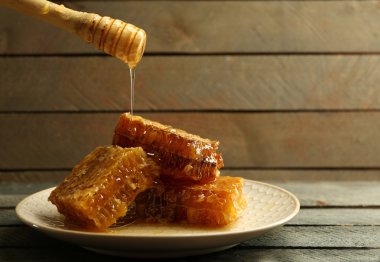 Ahşap arka plan üzerinde peteğin damlayan bal