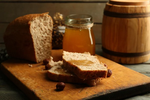 Pão fresco com mel no fundo de madeira — Fotografia de Stock
