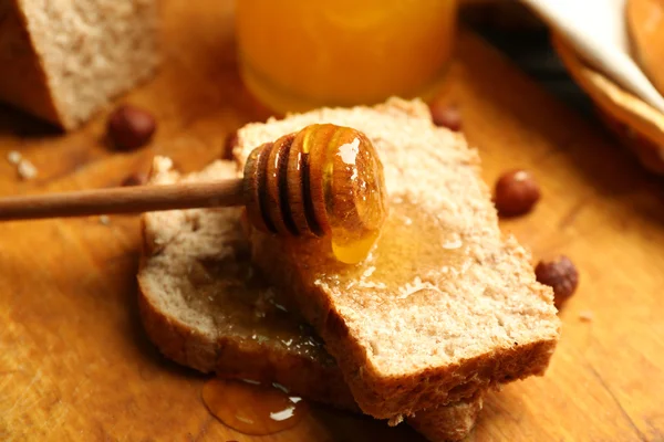 Färskt bröd med honung på trä bakgrund — Stockfoto