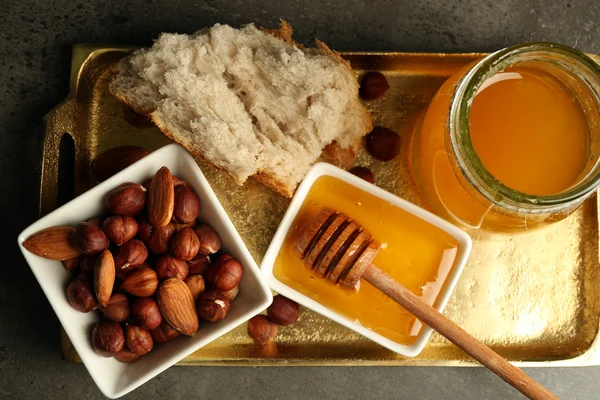 Burk med skål med honung och nötter på grå bakgrund — Stockfoto