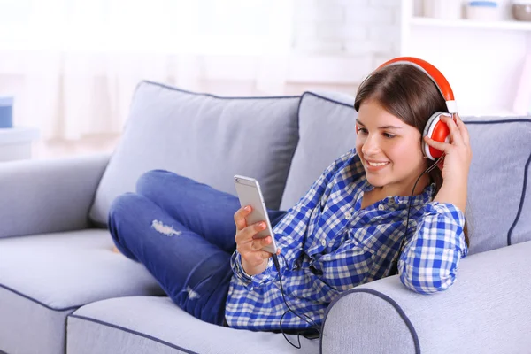 Menina bonita ouvindo música no sofá — Fotografia de Stock