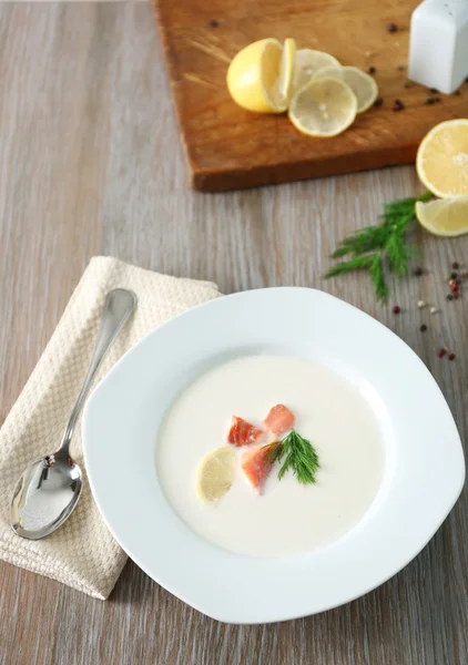 Вкусный сливочный суп с рыбой и нарезанным лимоном на белом столе в ресторане — стоковое фото